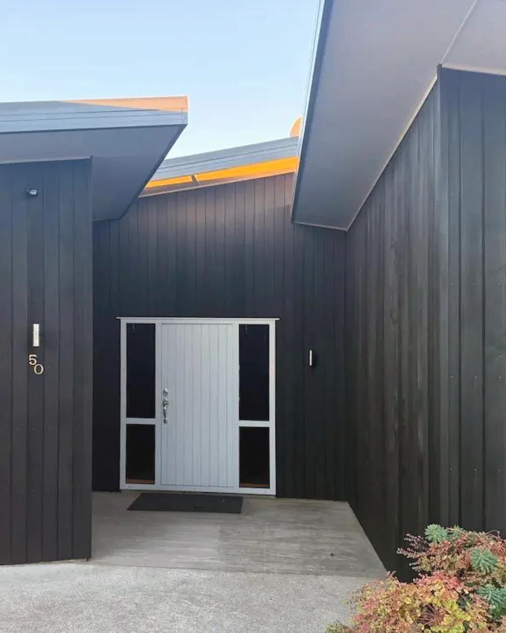 Restored dark cedar cladding around the entrance of an Albert Town home