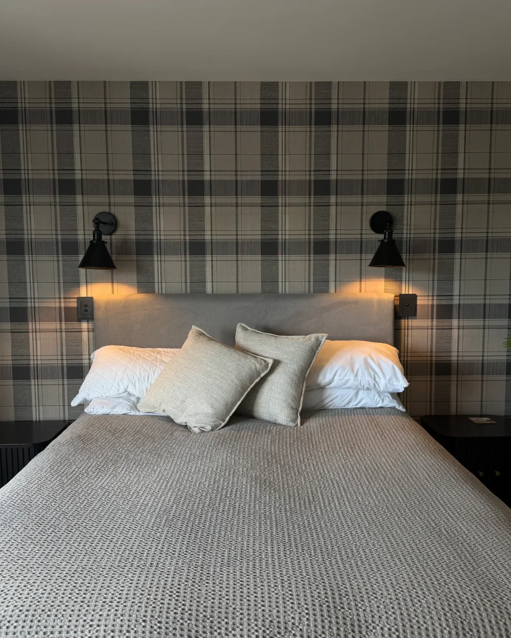 Tartan wallpaper behind a bed with matching bedside lights in Wānaka