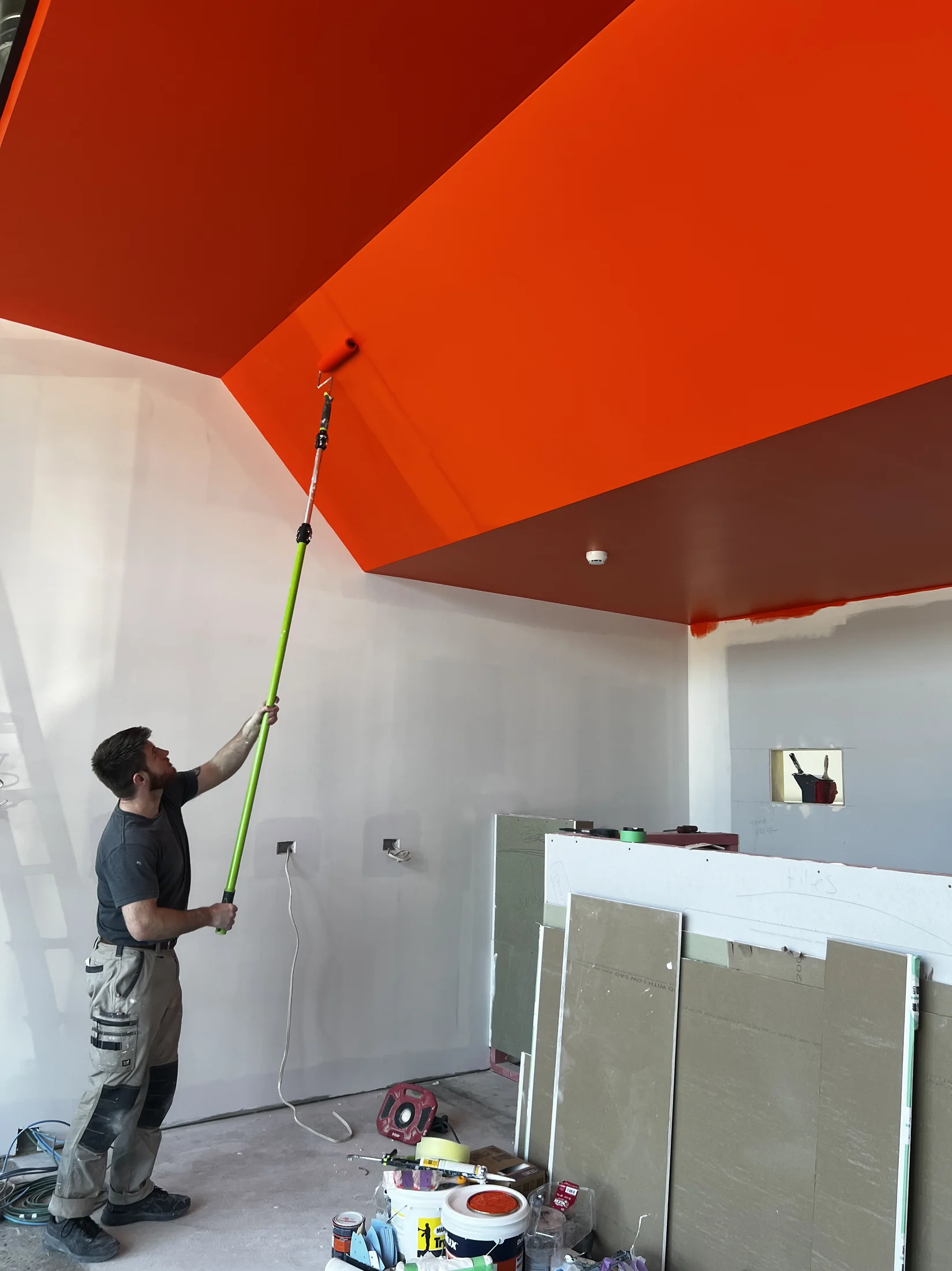 Tank Store Fitout, Three Parks Wanaka - Process 5: Painter Rolling Orange Feature Ceiling Tank Store Three Parks Wanaka